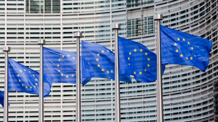 Europaflaggen wehen an Fahnenmasten vor einem Gebäude