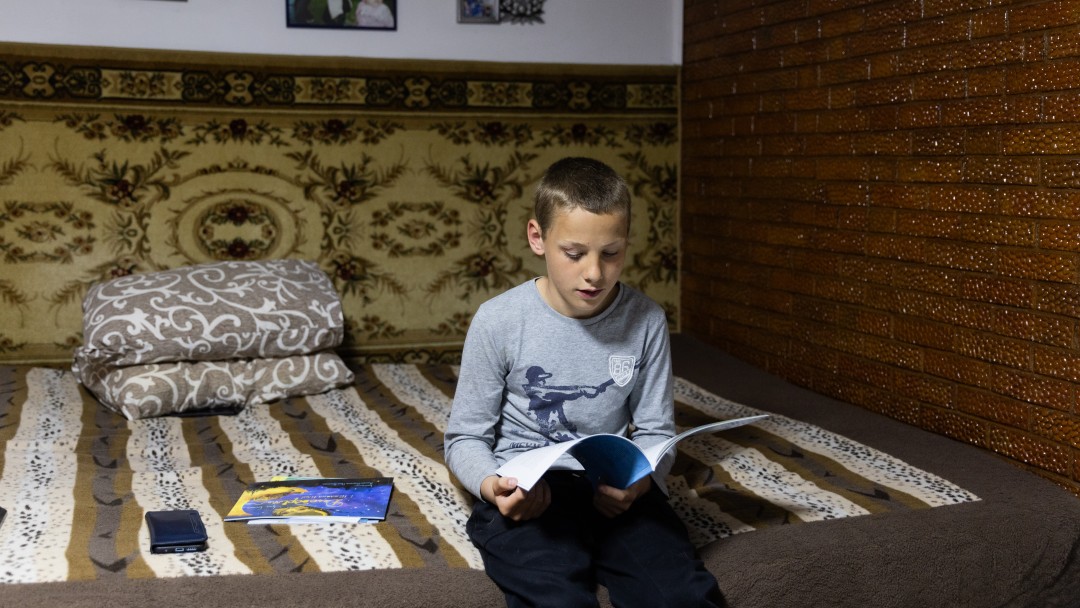 Ein Junge liest Bücher auf einem Bett