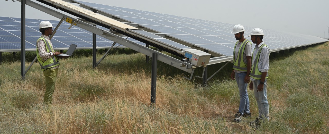 Techniker vor einem Solarpaneel auf einer Wiese