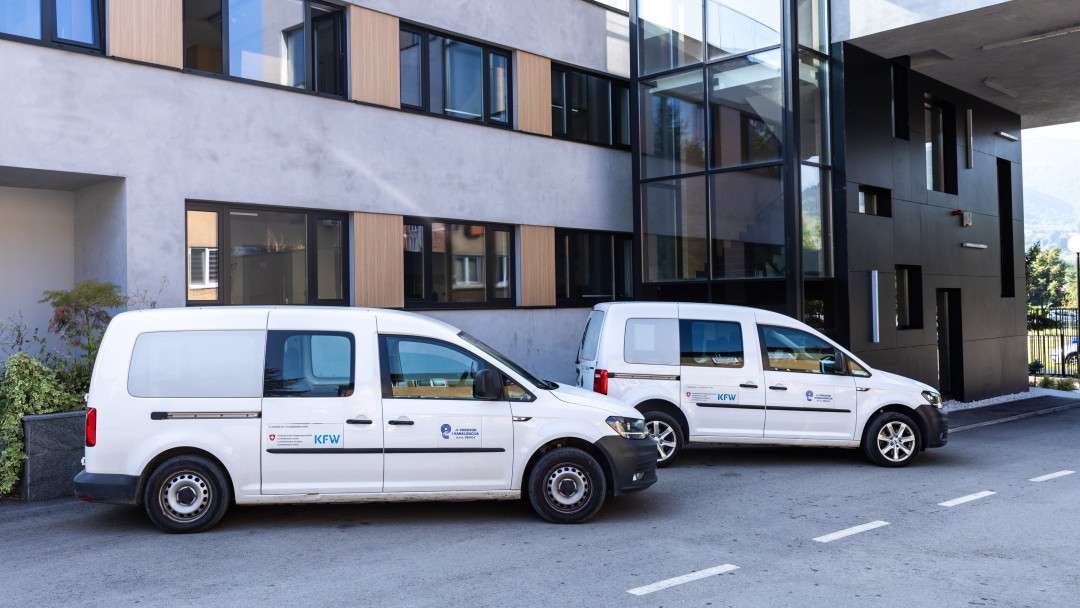 Zwei weiße Transporter stehen vor einem Bürogebäude