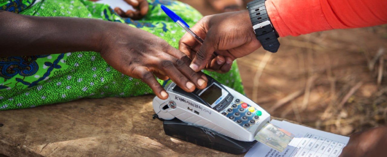 A woman puts her hand on a mobile EC device to receive a cash payment . 