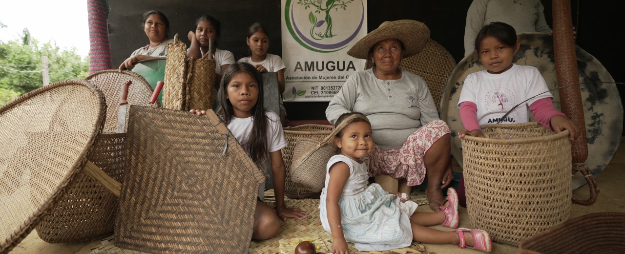 Women and girls sit next to baskets they have woven themselves.