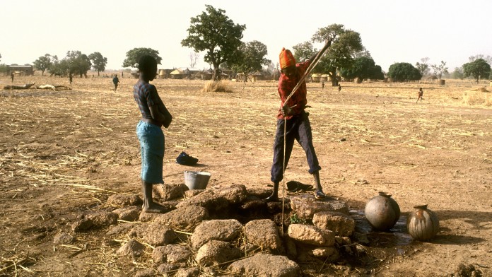 Two people take water from a well 