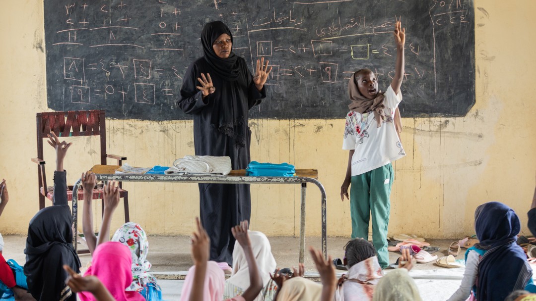 A teacher and a student standing in front of a class in a classroom