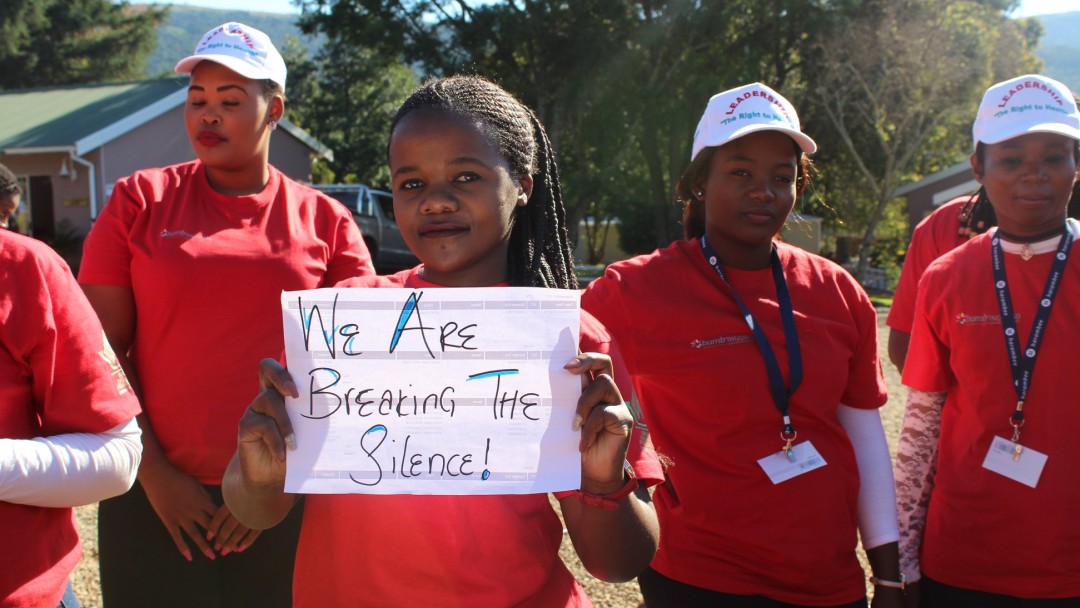 Eine junge Frau hält ein Schild hoch: "We are breaking the silence!"