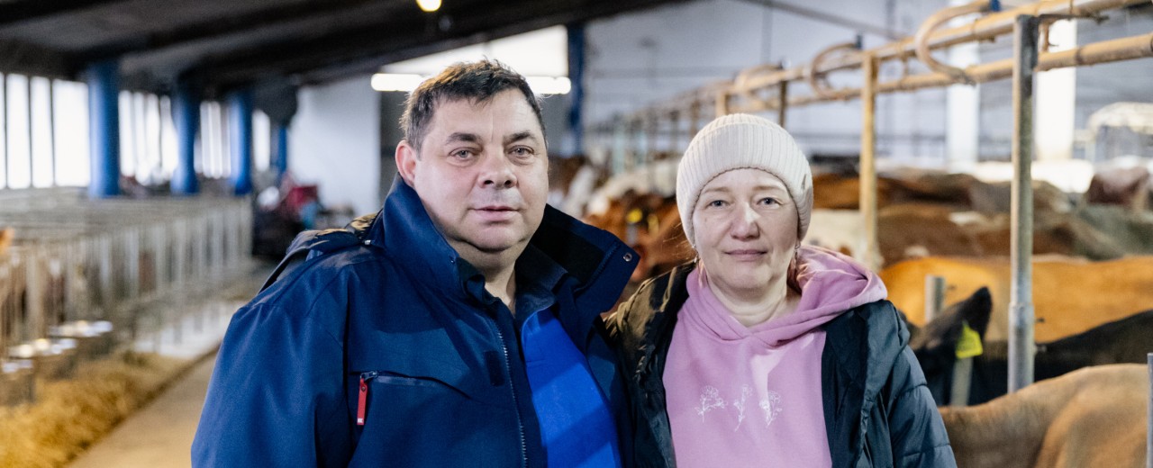 Ein Mann und eine Frau stehen im Mittelgang eines Kuhstalls.