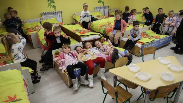 Kinder sitzen und liegen auf ihren Betten in einem Schutzraum eines Kindergartens in Schytomyr